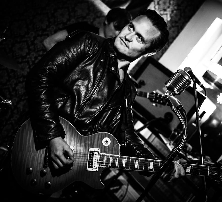 schwarz-weißes Foto von Ian Cox, mit Gitarre